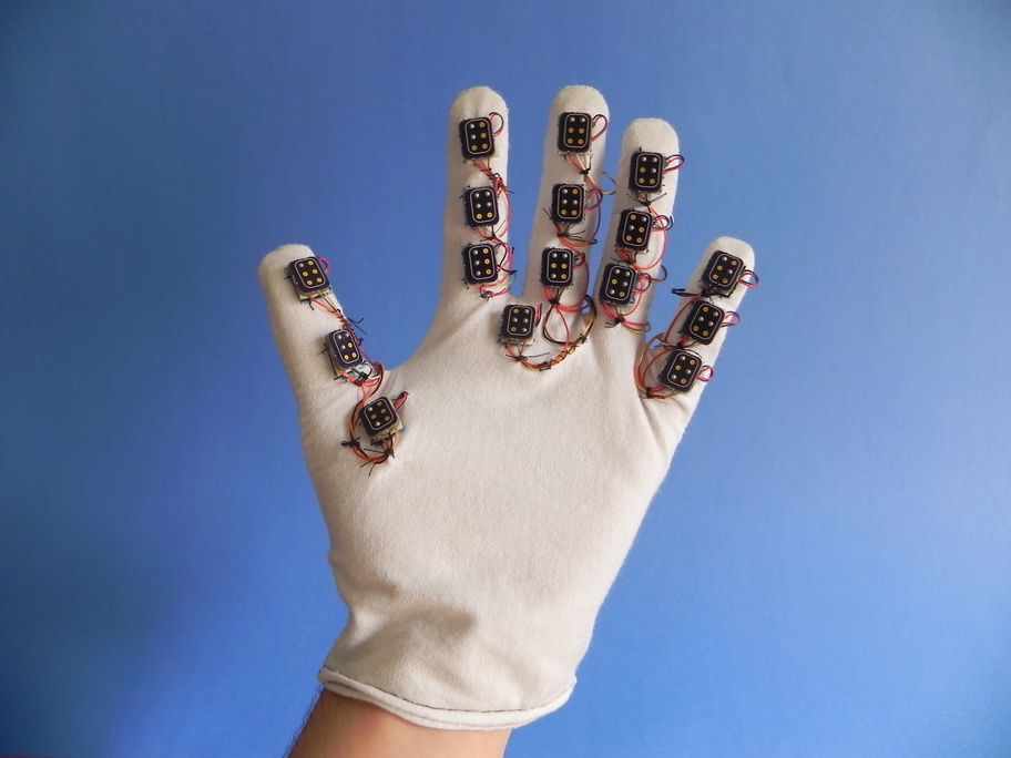 Fotografia da luva Helena Glove montada com seus componentes eletrônicos visíveis sobre o tecido.